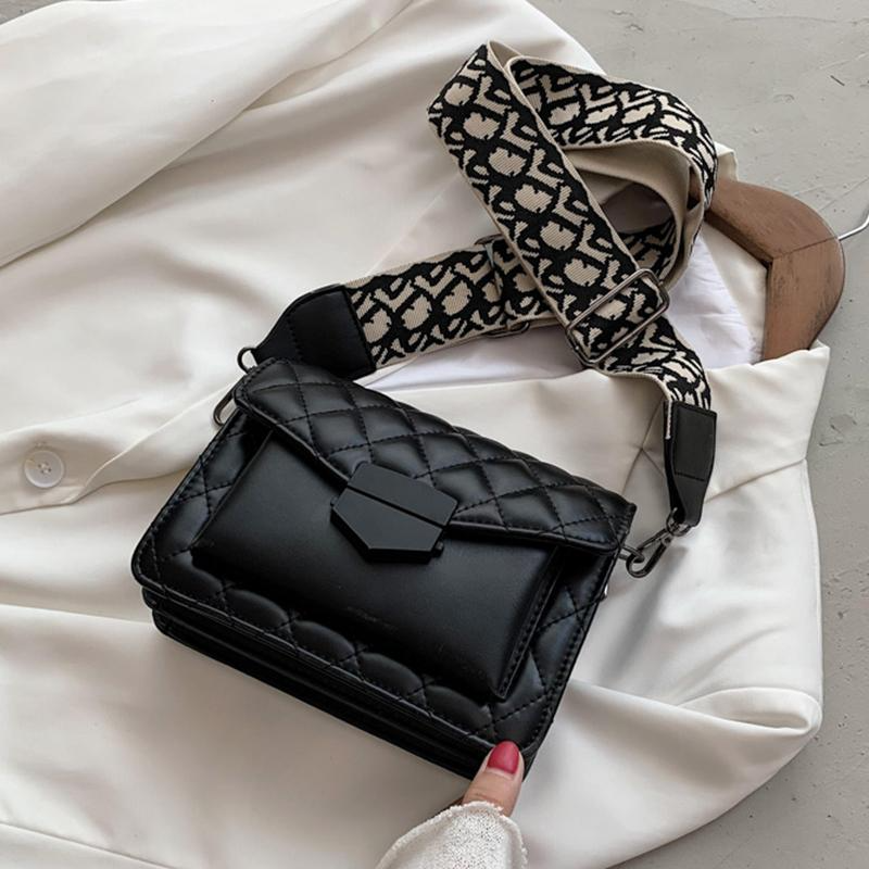 Black quilted handbag with patterned strap on a white surface