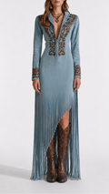 Long blue dress with intricate patterns and fringe, paired with brown boots on a white background